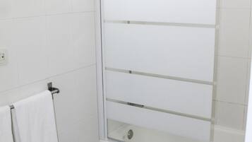 Een badkamer met een douchecabine van glas, een toilet en een handdoekhouder.