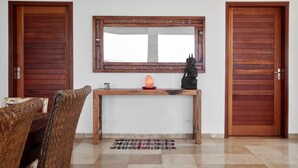Une pièce comprenant une console en bois, un miroir, une statue et deux portes en bois.