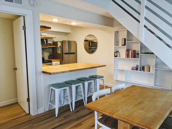 A compact kitchen with a central island, bar stools, and a dining table.