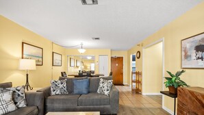 A living room with a gray sofa, a coffee table, and a lamp. There is a wooden cabinet and a plant on a side table.