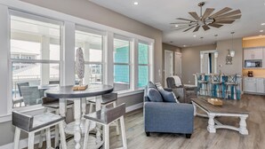 A spacious living area with a dining table, bar stools, and a sofa.