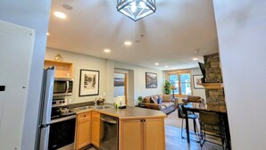 A modern kitchen with a central island, built-in appliances, and a stone accent wall. - Near Bike Park, Dining, Shops! Outdoor Hot Tubs! (Keystone)