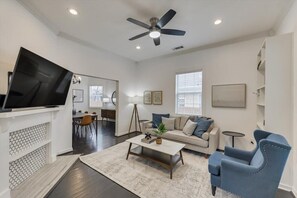 A living room with a TV, sofa, coffee table, and blue armchair.