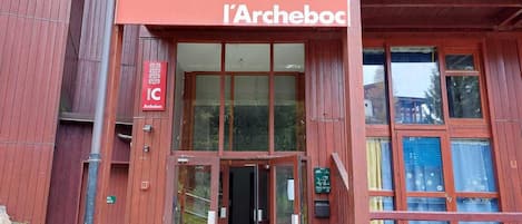 Un edificio rojo con un letrero que dice 'l'Archeboc' y una entrada de vidrio.