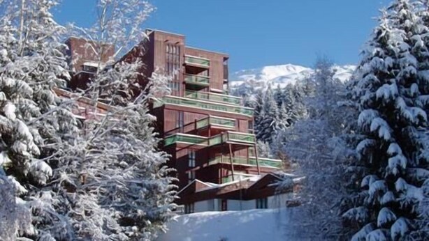 A multi-story building with balconies, surrounded by snow-covered trees and a clear sky. - 50m from resort center, 12nd floor, view firs, balcony, tv, 29m², Les Arcs (Les Arcs)