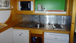 A compact kitchenette with a sink, stove, microwave, and a coffee maker. - 50m from resort center, 12nd floor, view firs, balcony, tv, 29m², Les Arcs (Les Arcs)