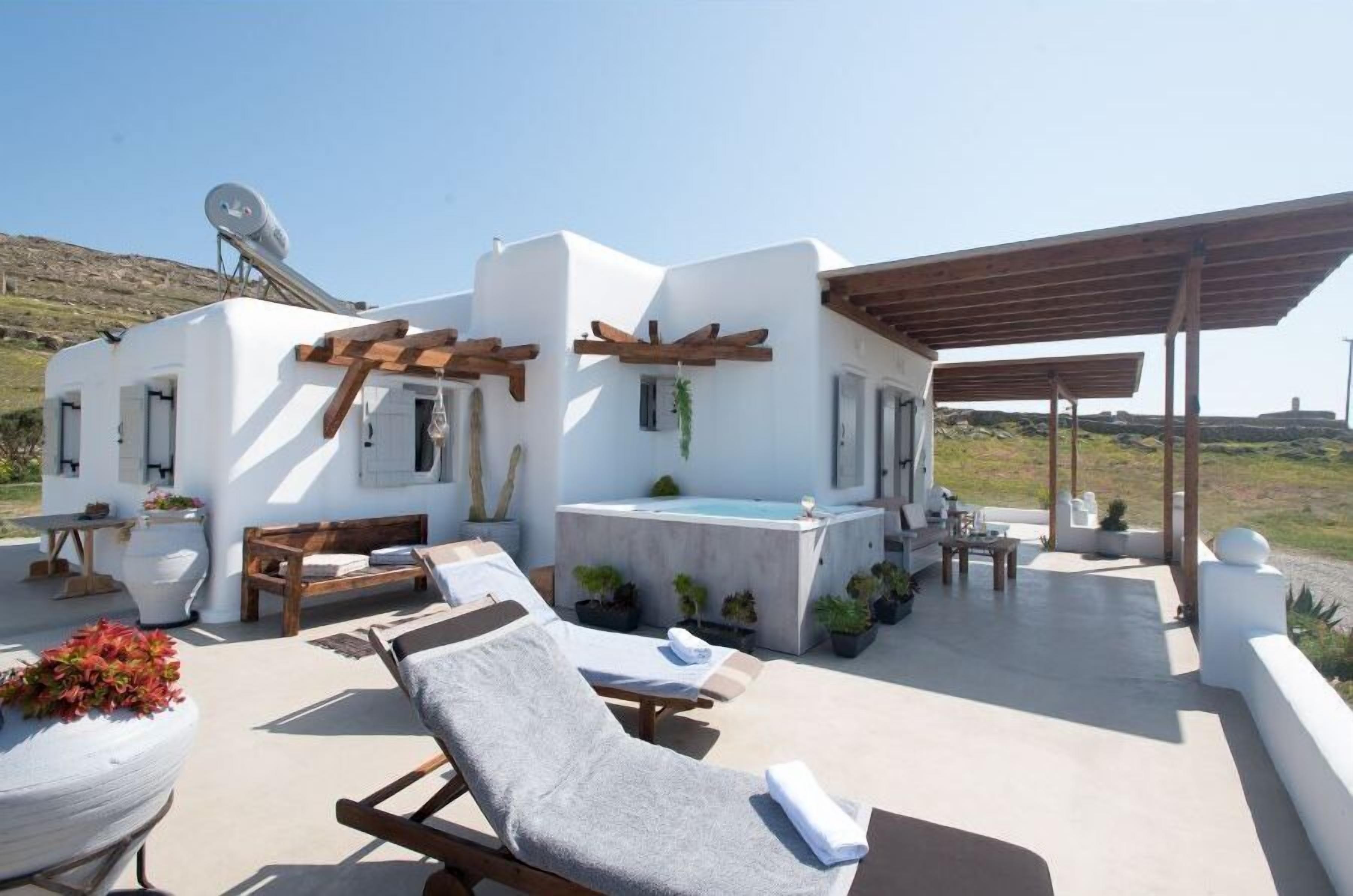 Una villa moderna con piscina, mobiliario exterior y una pérgola.