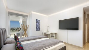 Ett modernt sovrum med en säng, ett skrivbord och en tv.