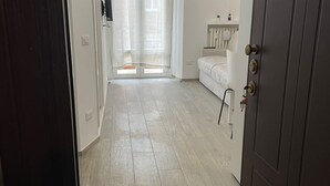Ein Flur mit Holzboden, der zu einem Zimmer mit einem Bett und einem kleinen Tisch führt.