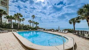 A swimming pool with a view of the ocean, surrounded by palm trees and lounge chairs. - Seascape 9 Luxury 2BR Beachfront Condo (North Redington Beach)