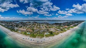 Luftaufnahme einer Küstenstadt mit Strand, blauem Himmel und ruhiger See.