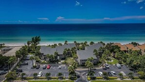 Ein Hotel direkt am Strand mit Parkplatz, Palmen und Meerblick.