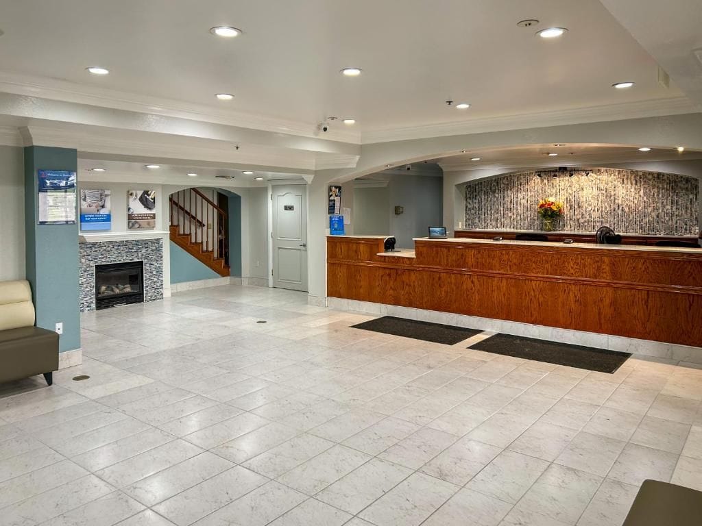 A spacious lobby with a reception desk, a fireplace, and a staircase.