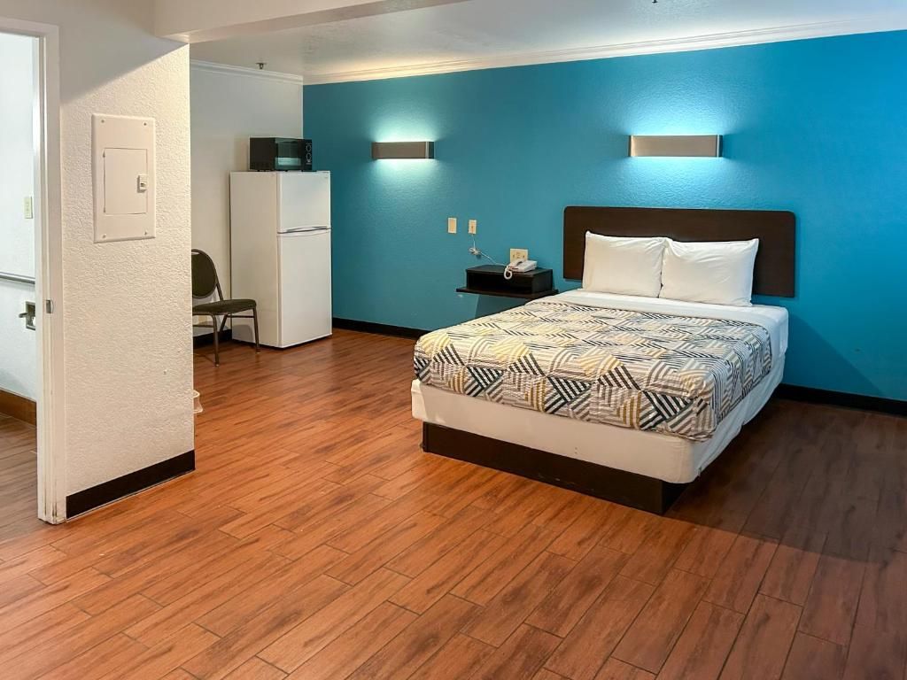 Une chambre d’hôtel équipée d’un lit, d’un bureau, d’une chaise, d’un four à micro-ondes et d’un réfrigérateur.