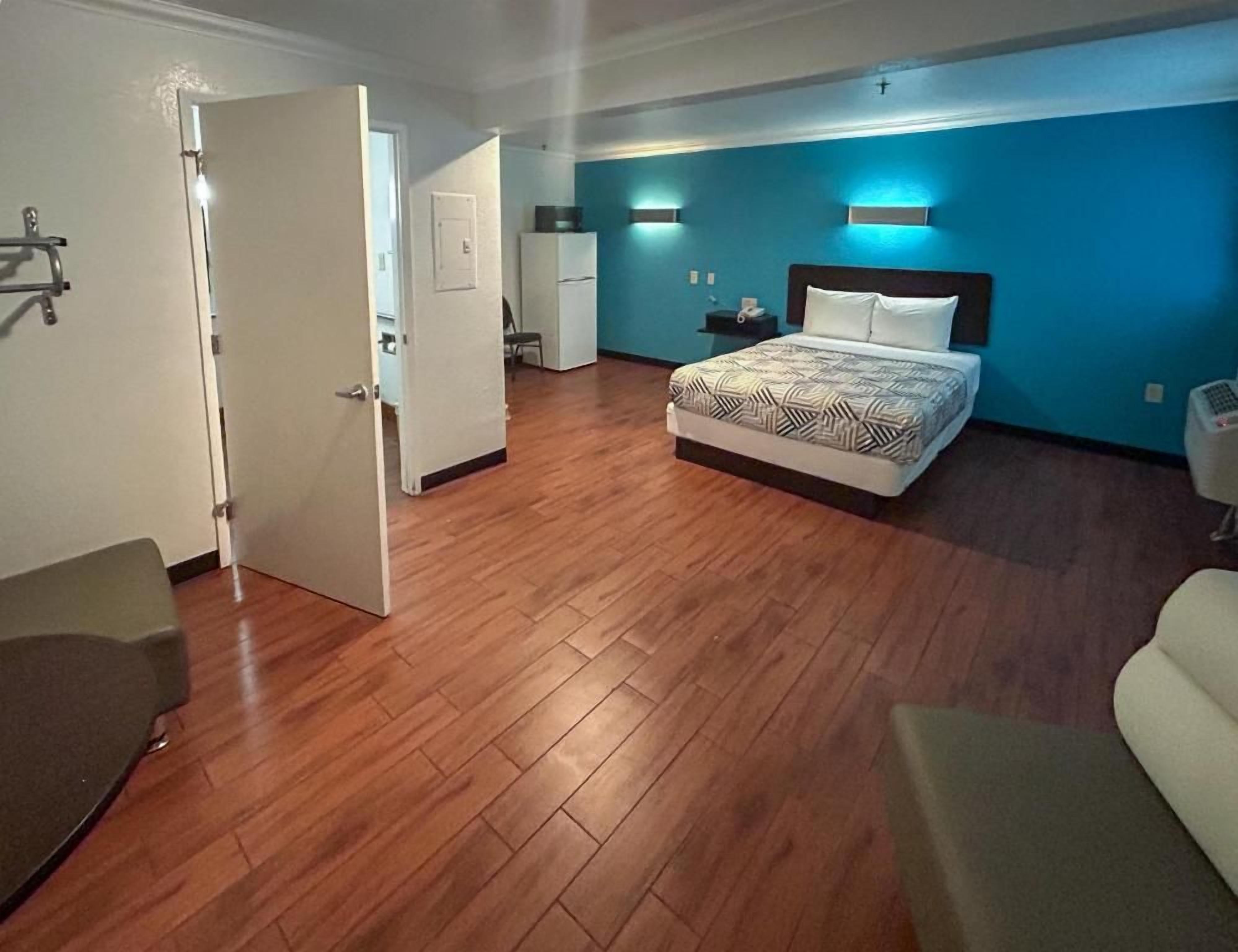 A hotel room with a bed, a desk, a chair, and a wardrobe.