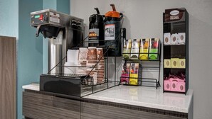 A coffee station with a coffee machine, a grinder, and various coffee pods.
