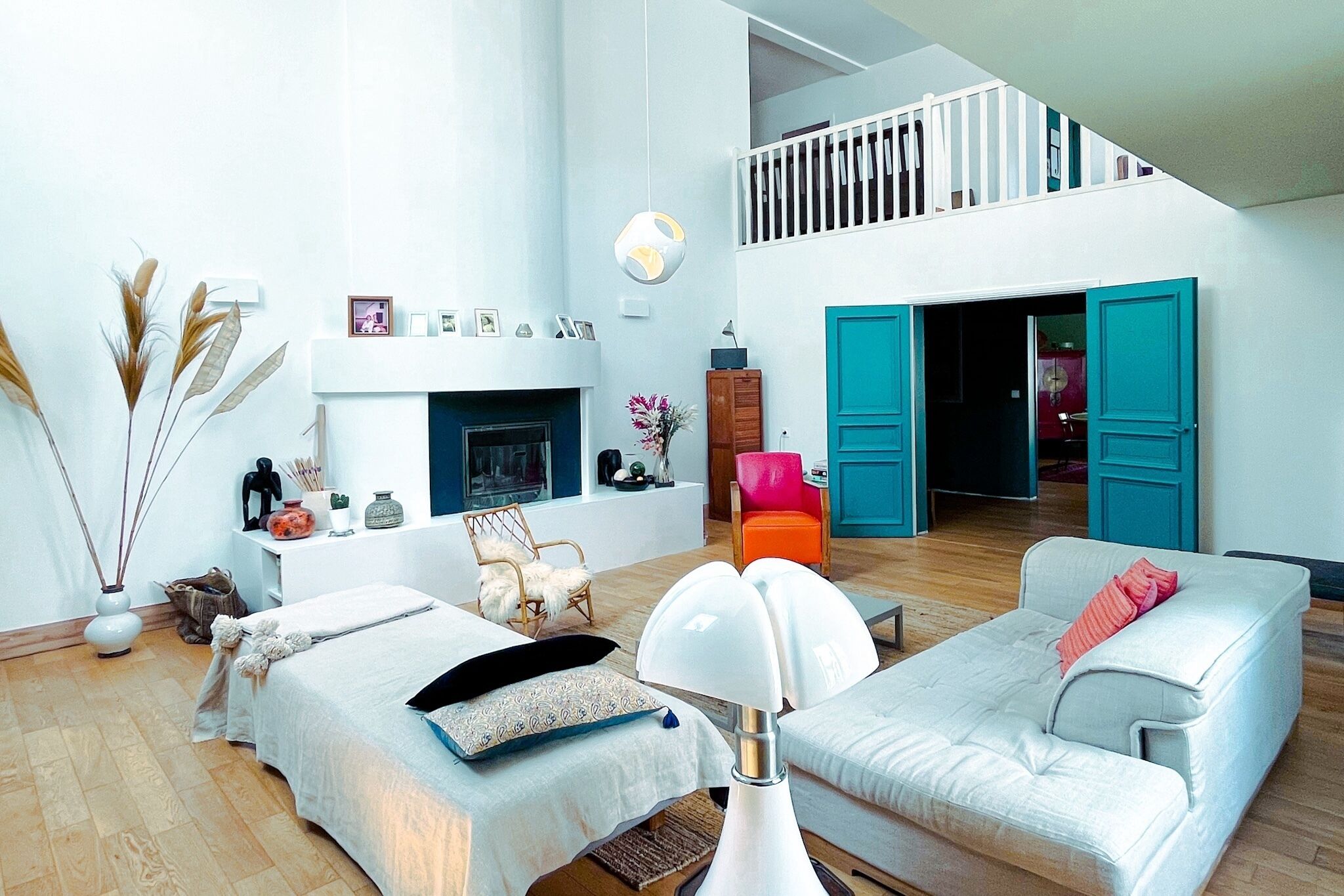 Een ruime woonkamer met een open haard, een bank, een fauteuil en een eethoek.