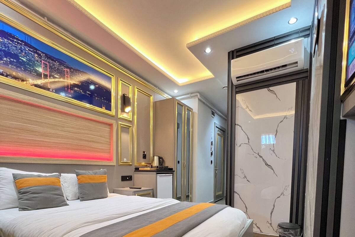 A modern hotel room with a large bed, a nightstand, a desk, and a bathroom with a marble wall.