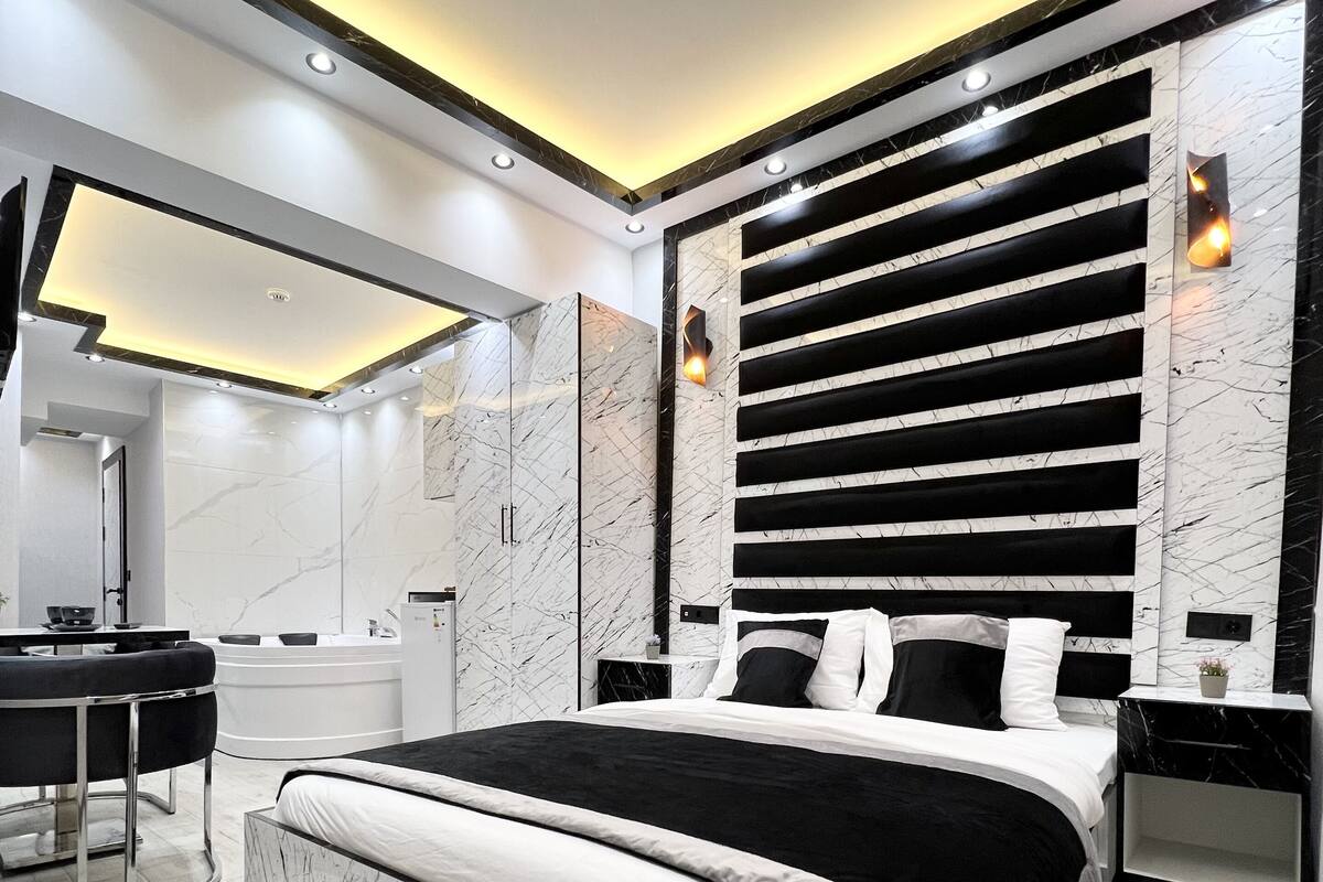A modern bedroom with a large bed, a vanity, and a built-in desk.