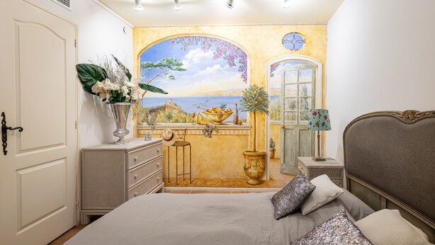 Un dormitorio con cama, cómoda, tocador y un ventanal con vistas.