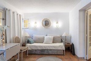 A bedroom with a bed, bedside lamps, a mirror, and a window.