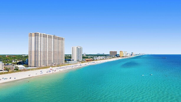 A coastal cityscape with a beach, high-rise hotels, and a clear blue sky.