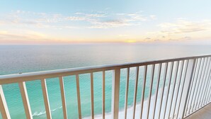 A balcony with a view of the ocean and a sunset.