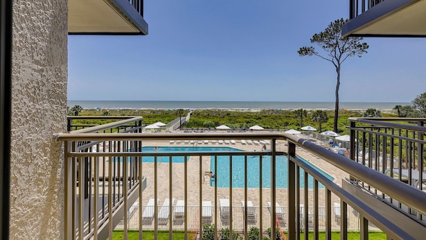 Un balcón con vista a una piscina y la playa.