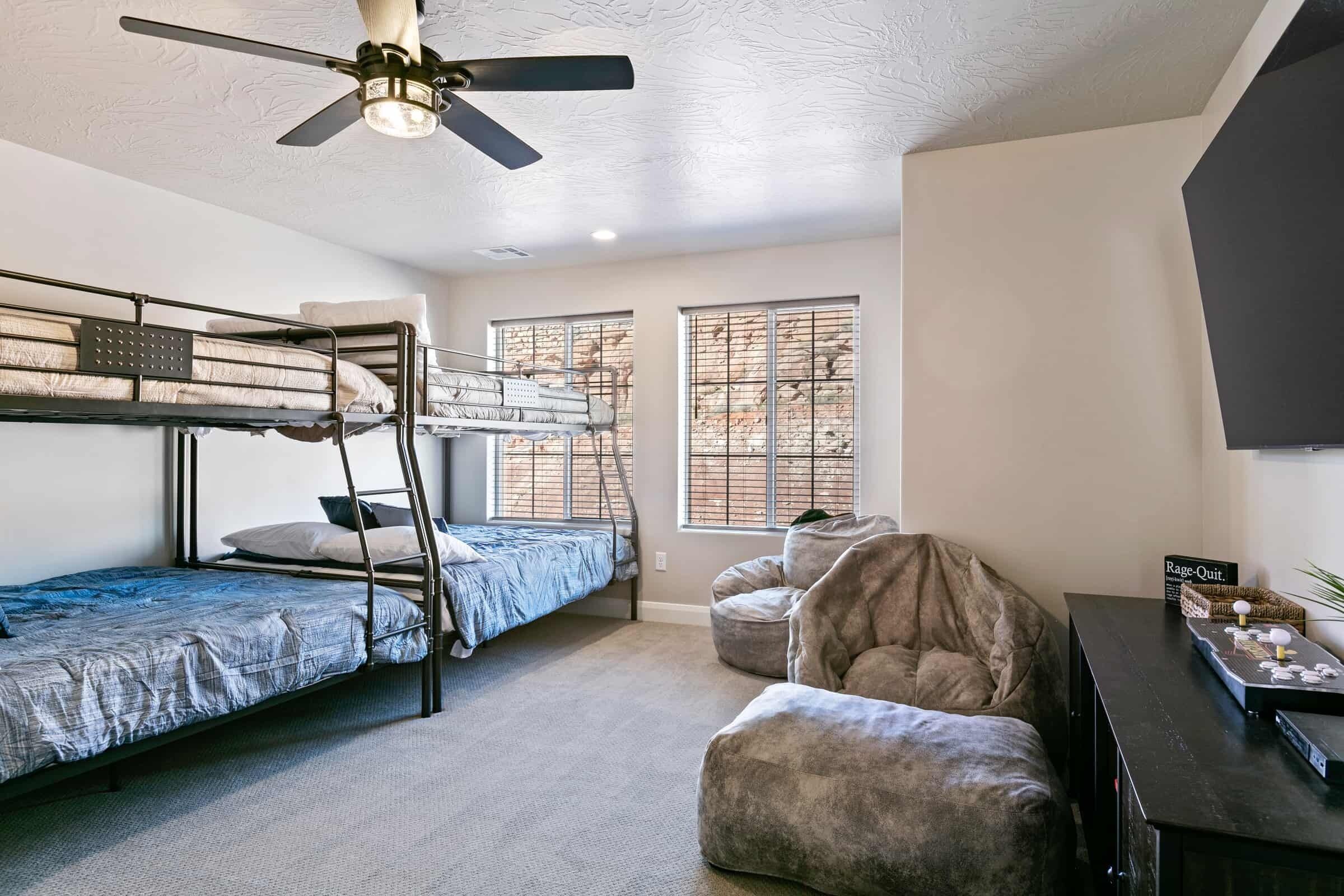 A dorm-style room with bunk beds, a ceiling fan, and a desk with a computer.