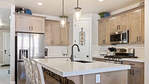 Una cocina moderna con armarios de madera, electrodomésticos de acero inoxidable e iluminación colgante.