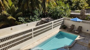 Una piscina con borde de baldosas, rodeada de sillas de descanso y una pequeña mesa.