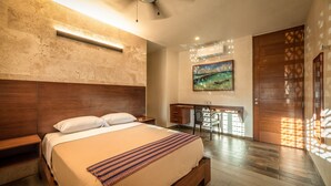 Un dormitorio con una cama grande, cabecera de madera, mesitas de noche, un escritorio con silla, un cuadro en la pared y una puerta corredera.