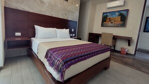 Un dormitorio con una cama grande, cabecera de madera, una mesita de noche, un escritorio y un aire acondicionado.
