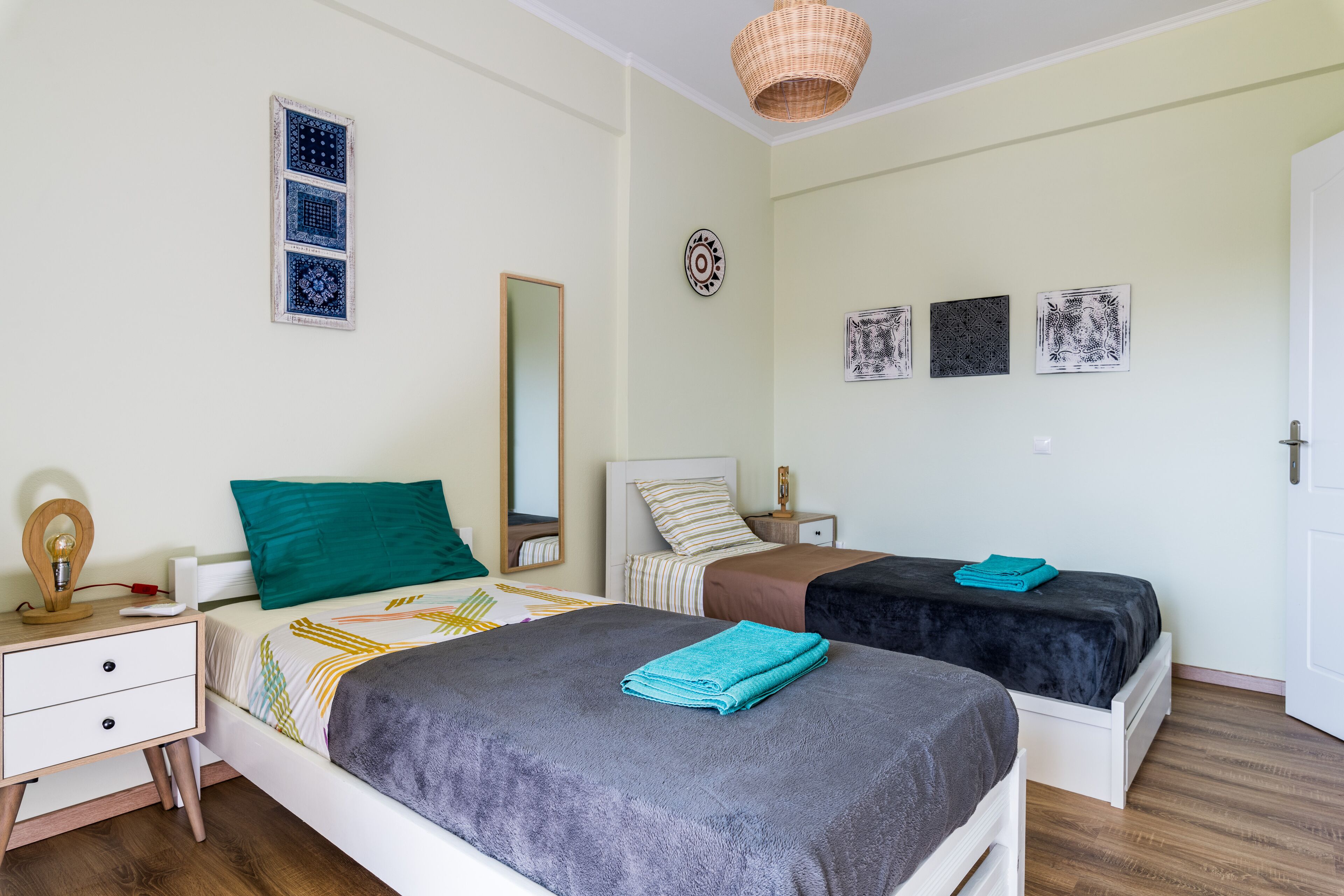 Une chambre avec deux lits, une table de chevet, une commode, un miroir et des éléments décoratifs sur les murs.