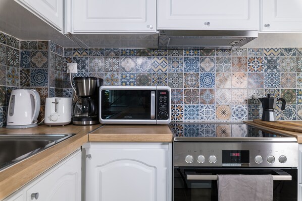 A kitchen with white cabinets, a microwave, a coffee maker, and a toaster. - Alexander Apartments Airport (Spata-Artemida)