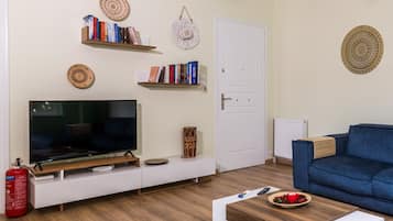 A living room with a TV, bookshelves, a blue sofa, and a coffee table.