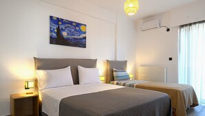 A hotel room with two beds, a painting on the wall, an air conditioning unit, and a window with curtains. - Alexander Apartments Airport (Spata-Artemida)