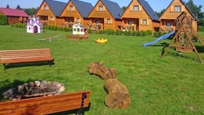 A campsite with wooden cabins, a playground, and a fire pit area. - Holiday homes with terraces, close to the beach (Jaroslawiec)