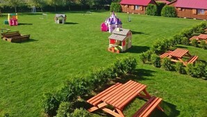 A grassy outdoor area with play structures, picnic tables, and small buildings. - Holiday homes with terraces, close to the beach (Jaroslawiec)