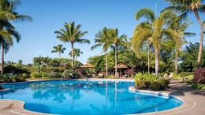 Ein Swimmingpool, umgeben von Palmen und Liegestühlen.