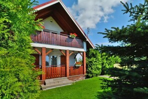 Chalet-style building with a spacious balcony and lush green surroundings.