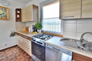 Kitchen features a gas stove, dishwasher, and large window with a view.