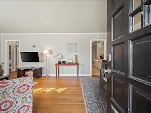 A living room with a TV, a lamp, a small table, and a sofa. - Charming 3BR Home in Brookside |Near Gathering Plc (Tulsa)