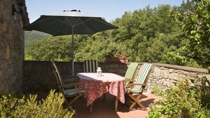 Un patio con una mesa, sillas y una sombrilla, junto a una pared de piedra.