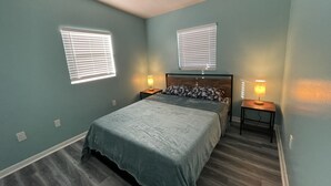 A bedroom with a bed, two bedside tables with lamps, and two windows with blinds. - Cheerful 3 Bed home w/ free parking, Wifi, Full Kitchen & Workstation. Sleeps 9 (Orlando)