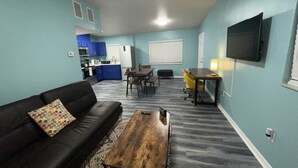 A compact living space with a sofa, coffee table, dining table, and kitchen area. - Cheerful 3 Bed home w/ free parking, Wifi, Full Kitchen & Workstation. Sleeps 9 (Orlando)