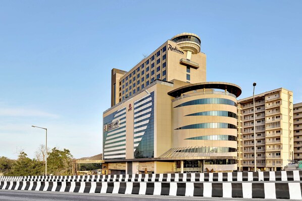 A modern hotel with a central tower, multiple floors, and a curved structure.