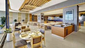 A modern hotel lobby with a central dining area, a reception desk, and a large chandelier. - Radisson Hotel Nathdwara (Nathdwara)