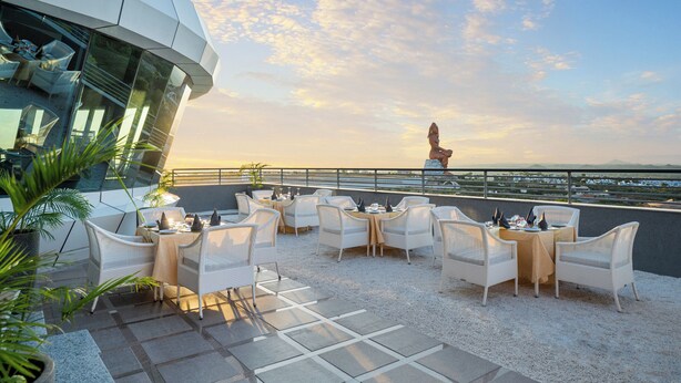 A rooftop terrace with white wicker furniture and a view of the sea. - Radisson Hotel Nathdwara (Nathdwara)