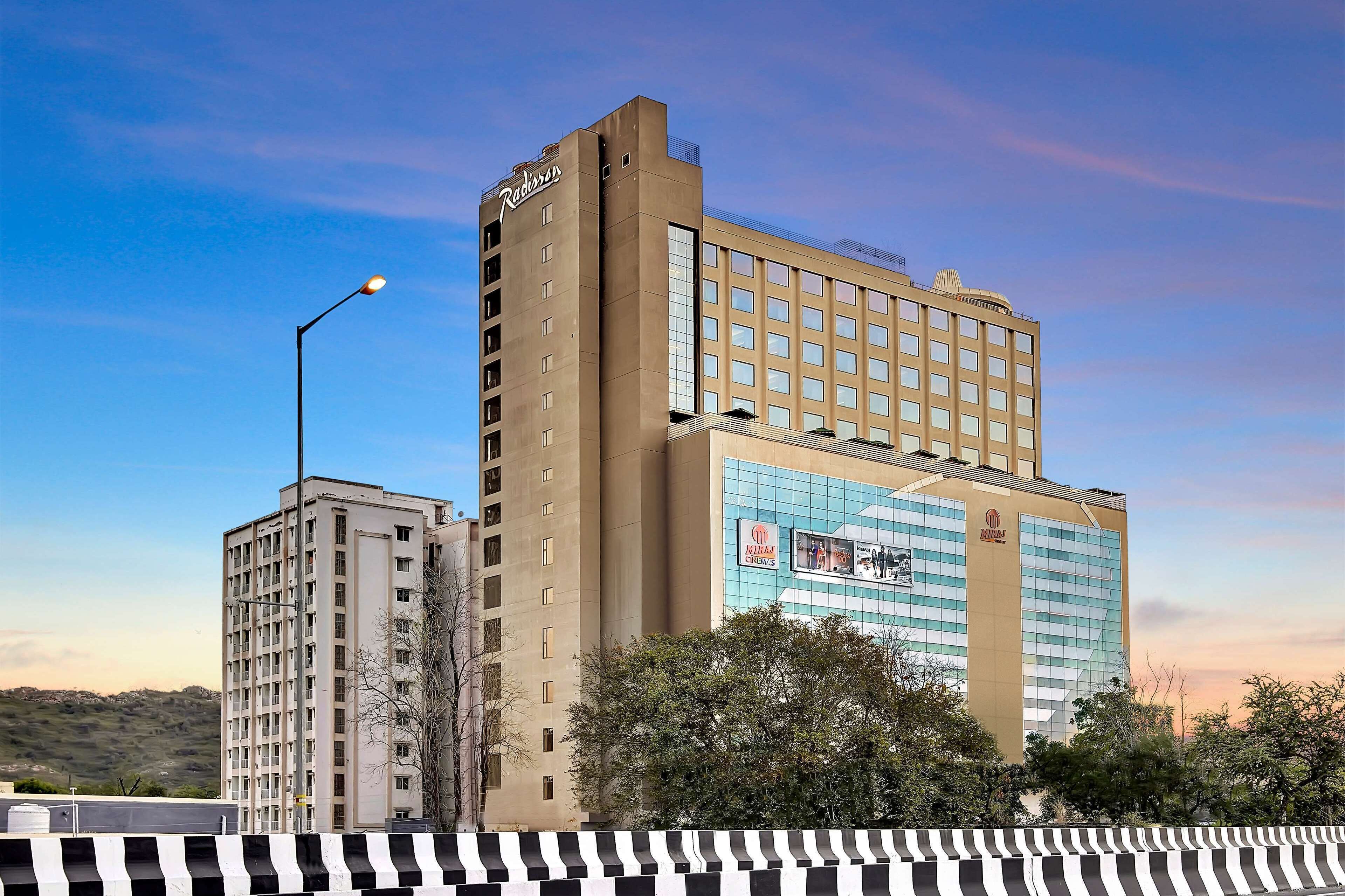 Un hotel con un llamativo letrero de 'Radisson', una fachada moderna y un gran letrero de 'KIRAZ' en el edificio.